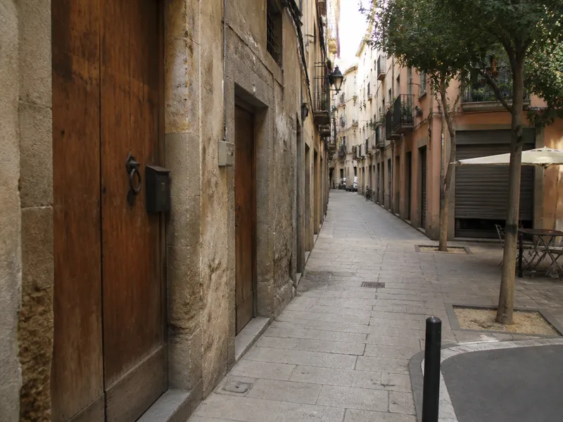 Calle en pendiente de Sarrià-Sant Gervasi con puertas de finca, Barcelona, sin peatones de frente.