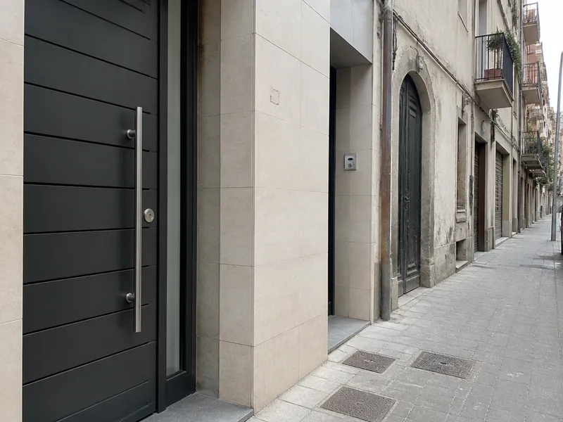 Calle de Sant Andreu con portales de finca y acera, Barcelona, sin rostros ni rótulos comerciales.
