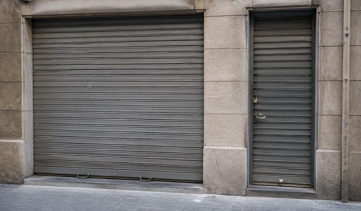Metal shutter and pedestrian door of a Barcelona shop, no brand lettering and no people.