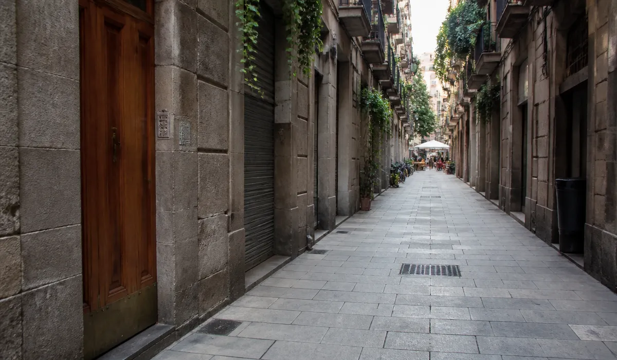 Calle de Barcelona con portales de piedra y puertas de madera, sin peatones de frente ni marcas comerciales.