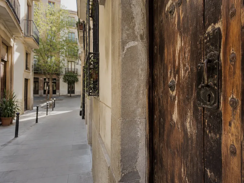 Puerta de madera hinchada en una calle estrecha de Gràcia.